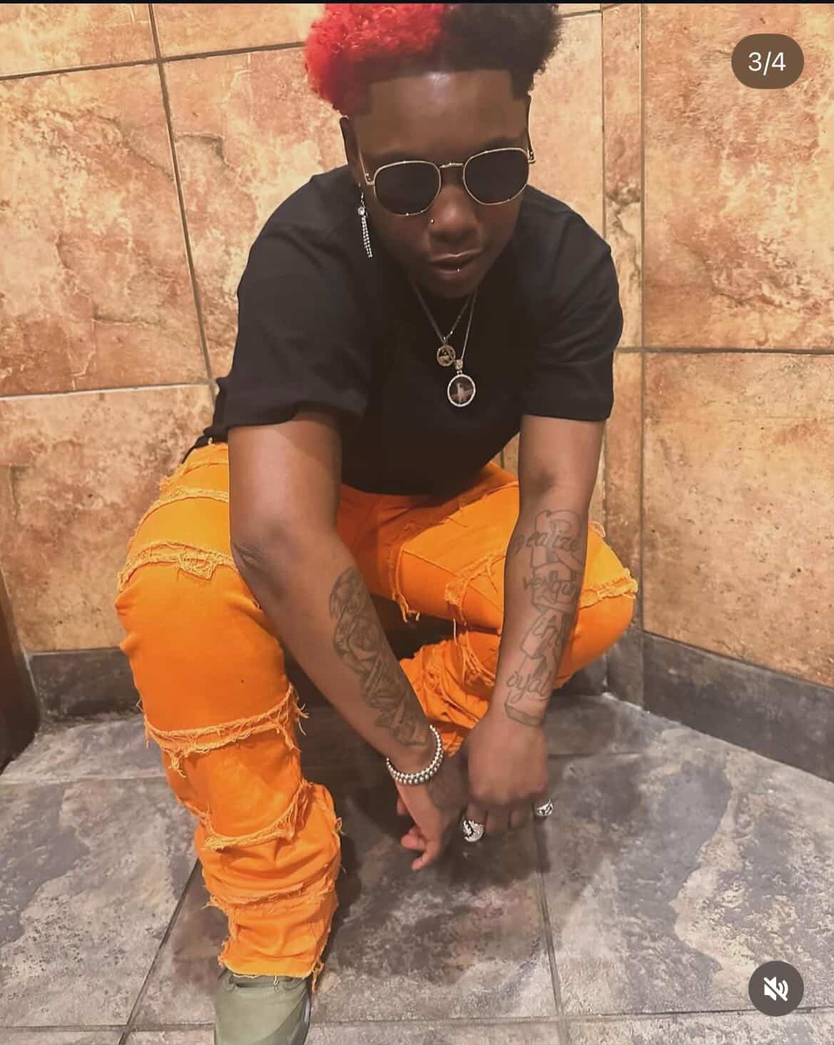 Booga Brim in sunglasses, red hair, orange pants, full-length pose