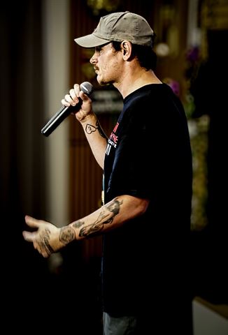 Kocain at RRL 2026, tattooed artist in black tee and tan cap singing into handheld mic in profile