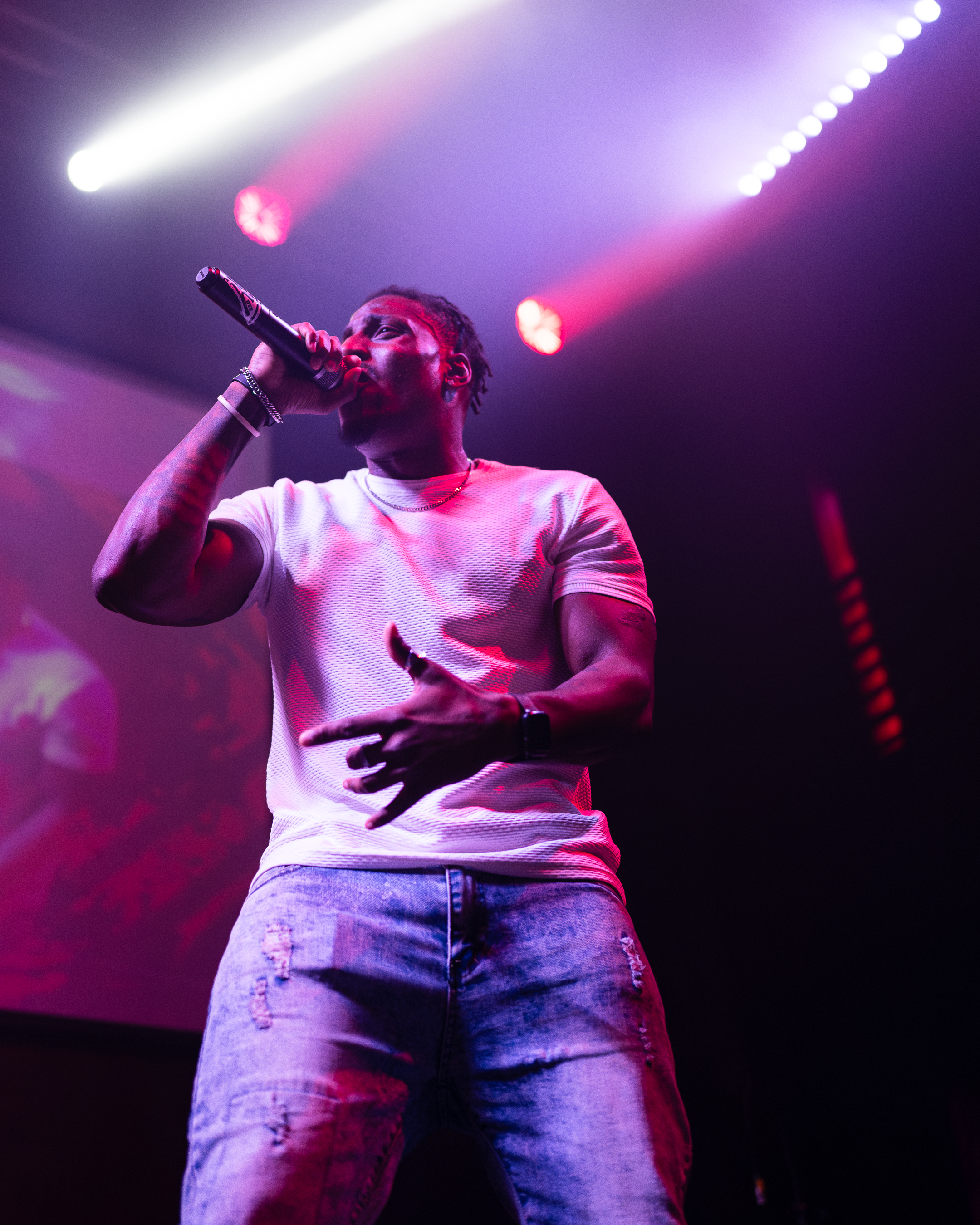 Tay No Tee performing live, microphone in hand under stage lights