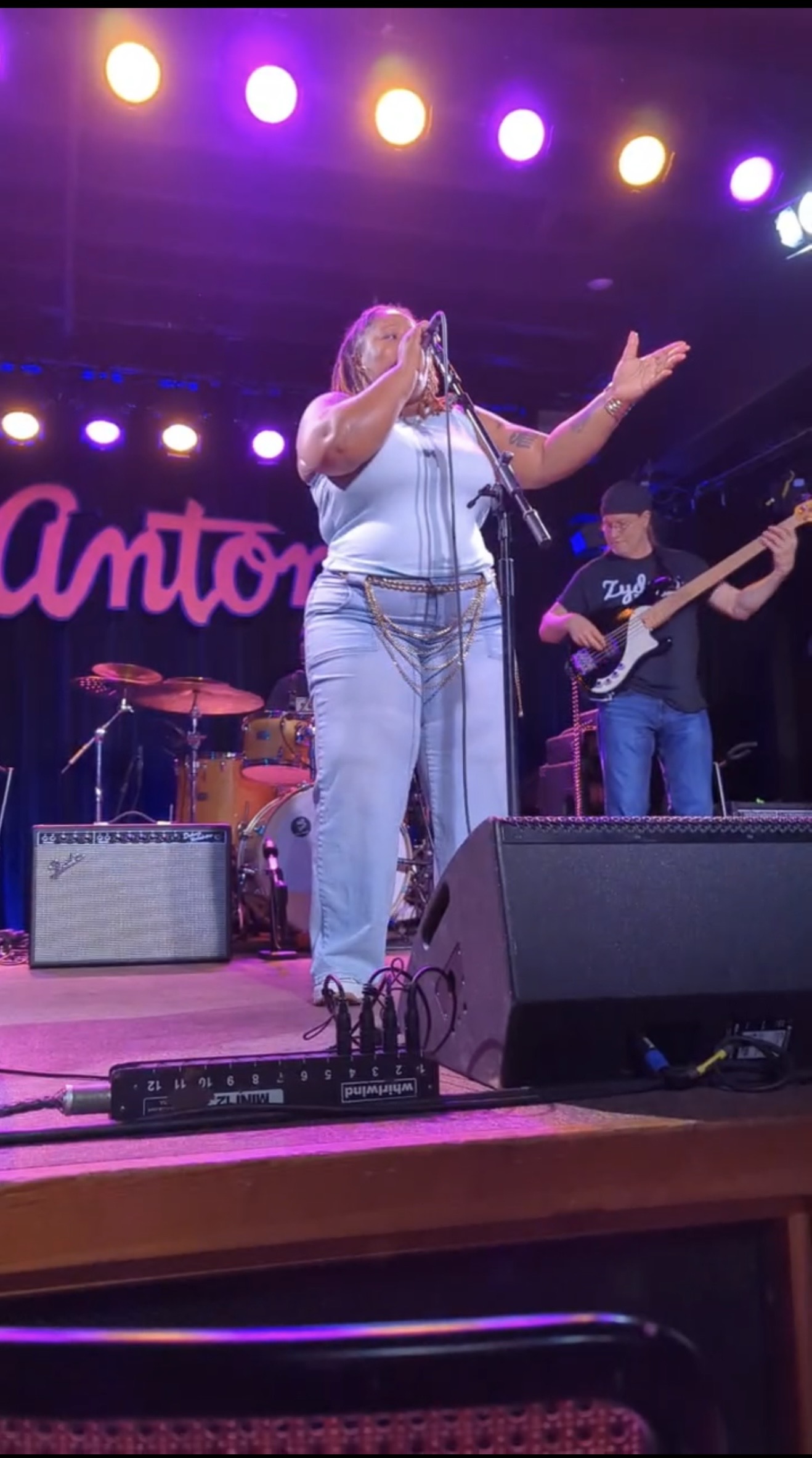 Tiffiny performing live on stage with hands raised, gold stage lighting